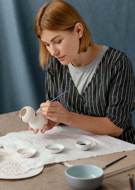 Woman painting pottery item  medium shot