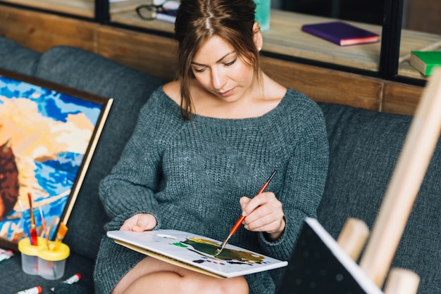 Woman painting sitting on couch