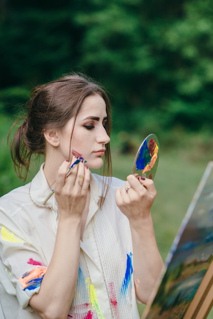 Woman painting with a paintbrush on her face