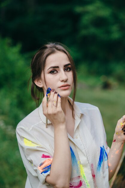 Woman painting with a paintbrush on her face