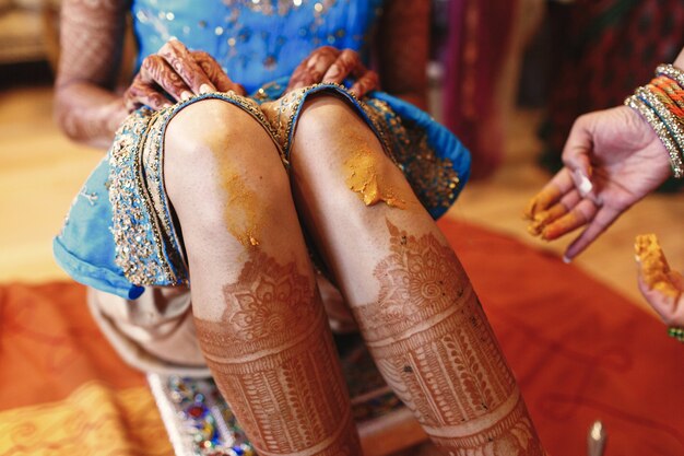 Woman paints bride's knees with turmeric