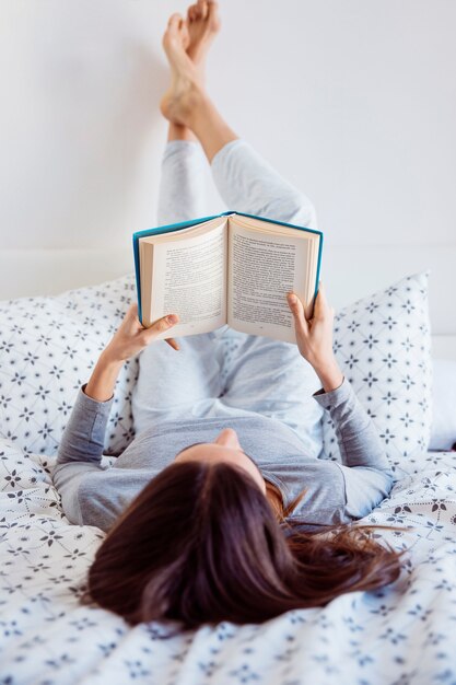 Женщина в пижаме, наслаждаясь чтением