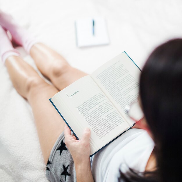 ベッドで読んでいるパジャマの女性
