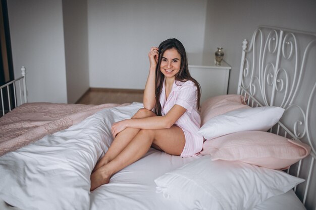 ベッドに座っているパジャマの女
