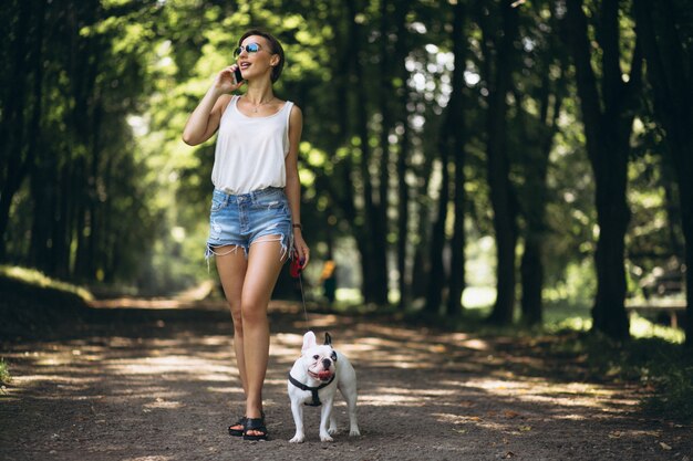 Woman in park with french bulldog talking on the phone