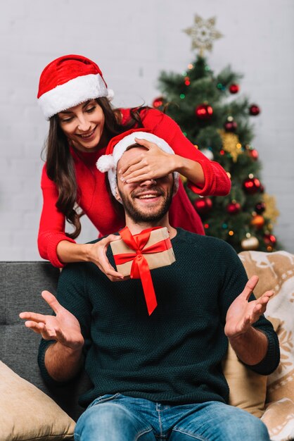 Woman in party hat closing eyes to happy man