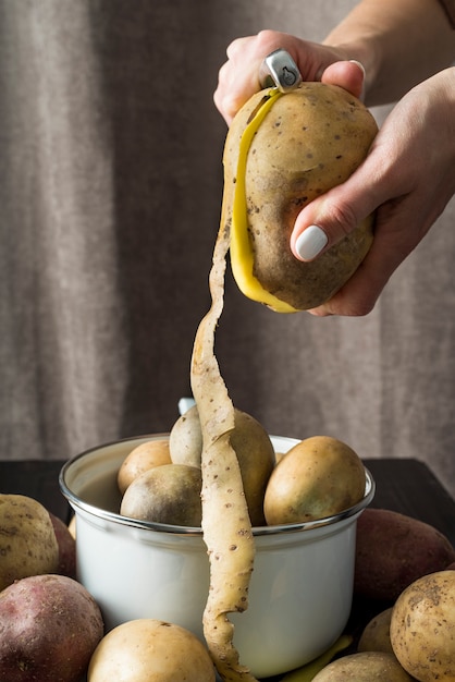 Woman peeling raw potatoes