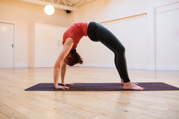 Woman performing chakrasana on exercise mat