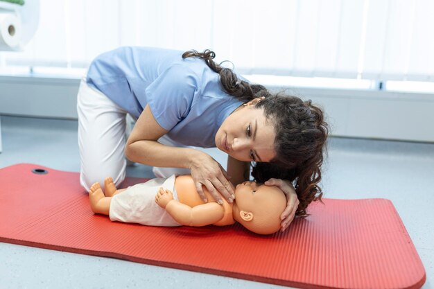 Woman performing CPR on baby training doll with one hand compression First Aid Training Cardiopulmonary resuscitation First aid course on cpr dummy