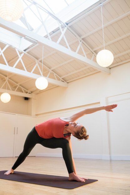 Woman performing extended side angle pose on exercise mat