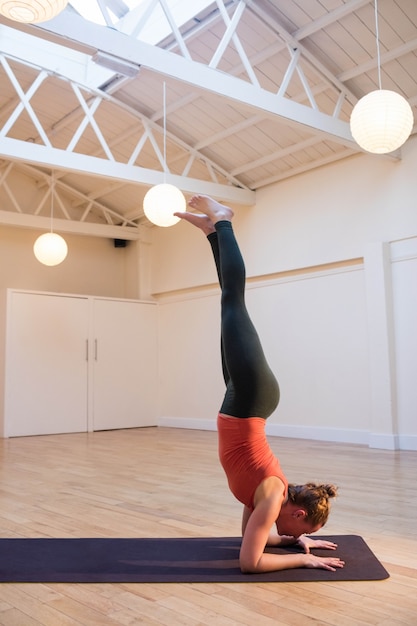 Woman performing handstand pose on exercise mat