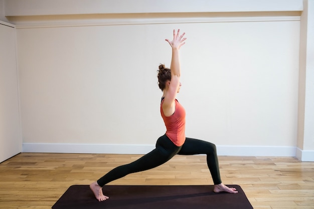 Woman performing warrior pose on exercise mat