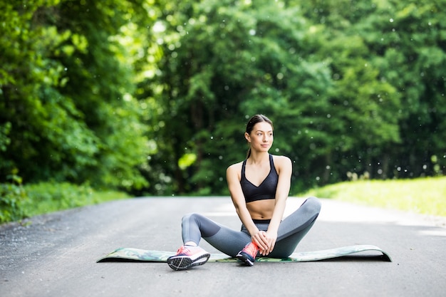 女性は屋外の公園でスポーツの前にストレッチを行います