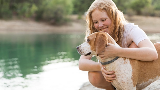 湖の横で犬をかわいがる女性