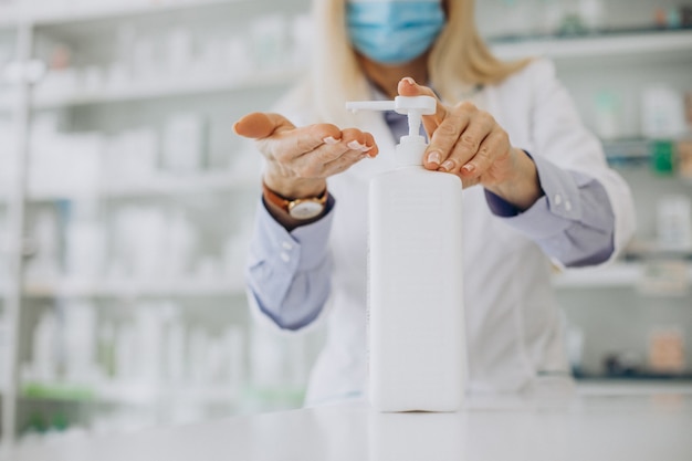 Free photo woman pharmacist using sanitizer at pharmacy