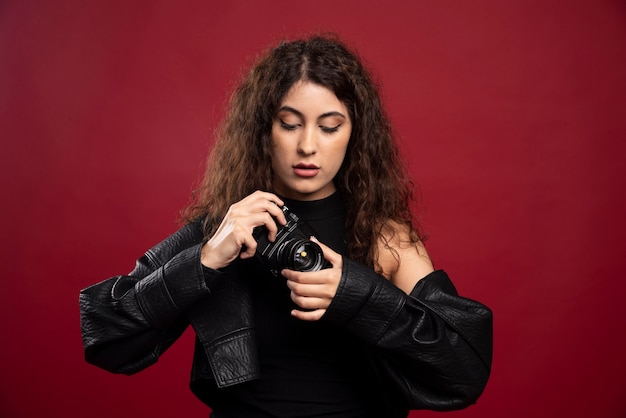 Женщина-фотограф во всем черном костюме с фотоаппаратом.