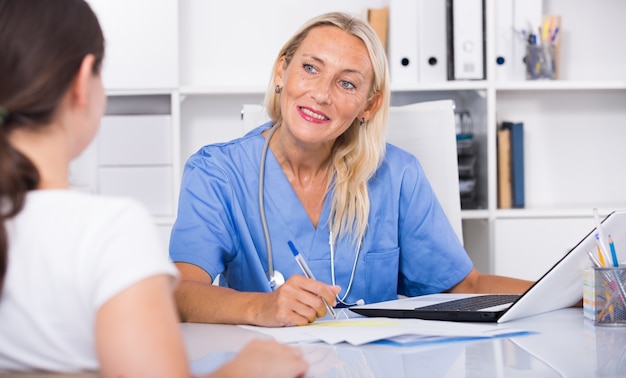 Woman physician consulting female in office