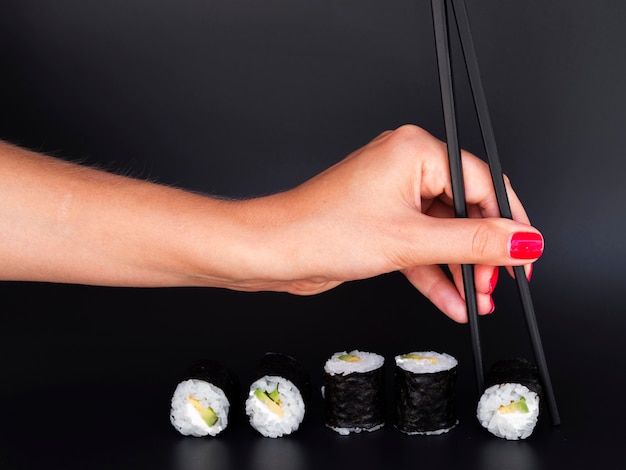箸で寿司を選ぶ女性