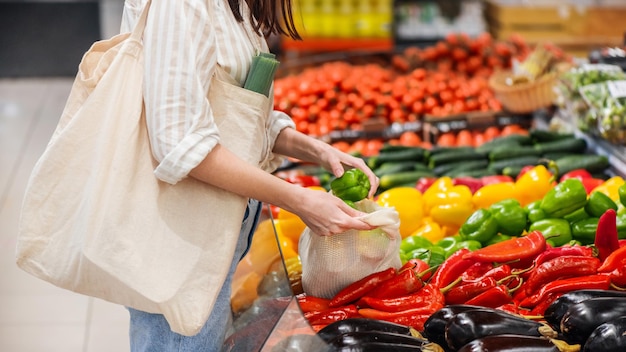 Donna che raccoglie peperoni in una borsa riutilizzabile tematica della giornata della terra dell'ecologia