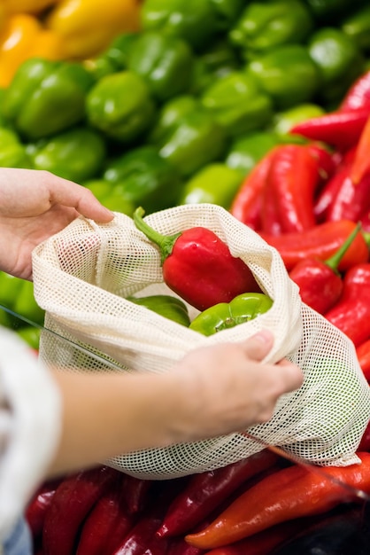 Woman picking bell peppers in a reusable bag Ecology Earth Day thematics