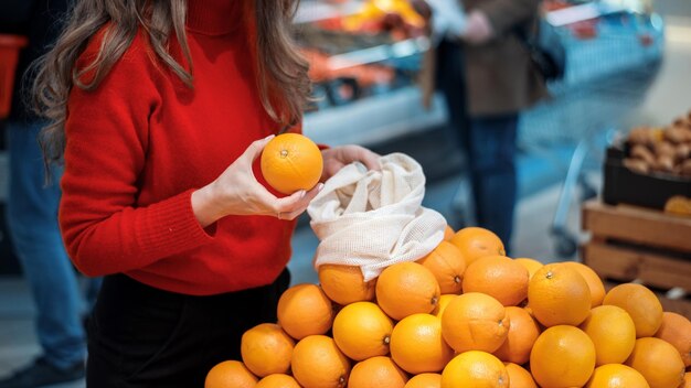 Женщина собирает апельсины в многоразовой сумке Экология Тематика Дня Земли