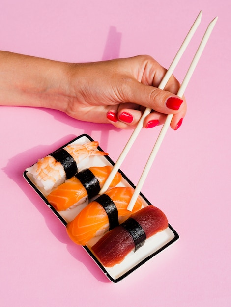 皿からサーモン寿司を選ぶ女性