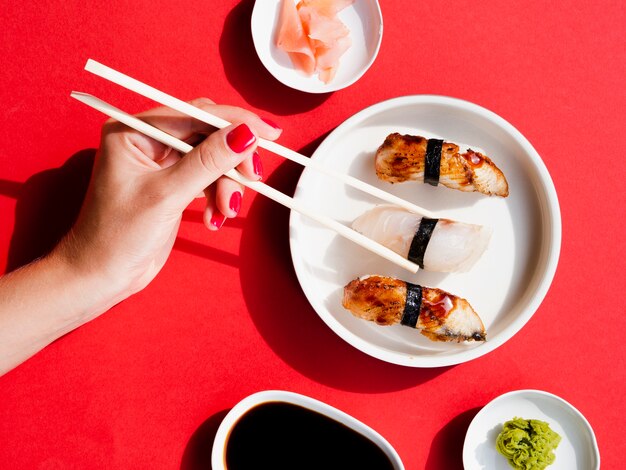 Woman picking a sushi from white plate