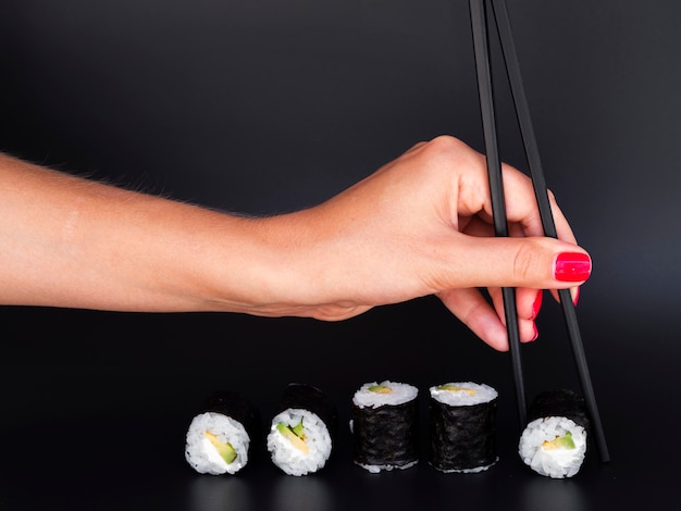 Foto gratuita donna che seleziona un rotolo di sushi con le bacchette