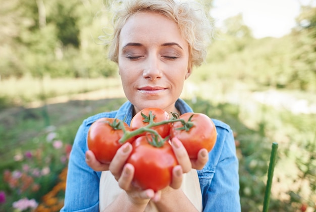 그녀의 정원에서 몇 가지 토마토를 따기 여자