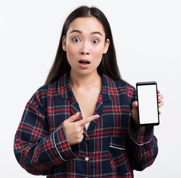 Woman in pijama pointing at phone