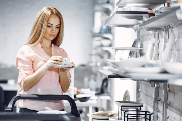 Woman in a pink blouse buys dishes in the store