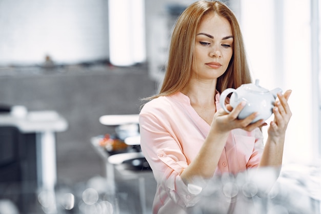 Woman in a pink blouse buys dishes in the store