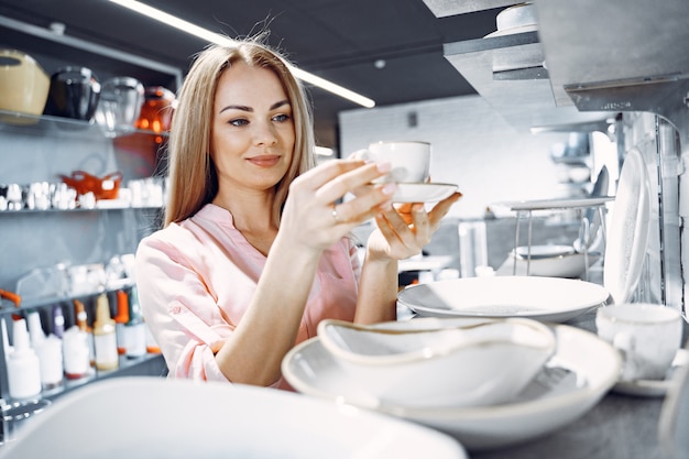 Woman in a pink blouse buys dishes in the store