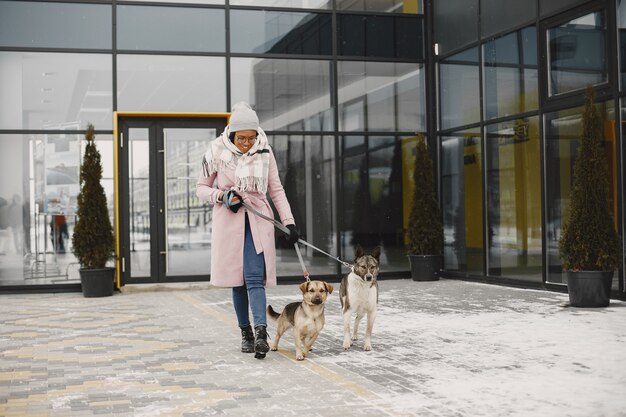 Женщина в розовом пальто, выгуливает собак