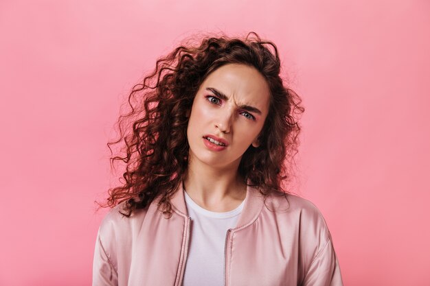 woman in pink outfit looks into camera with misunderstanding