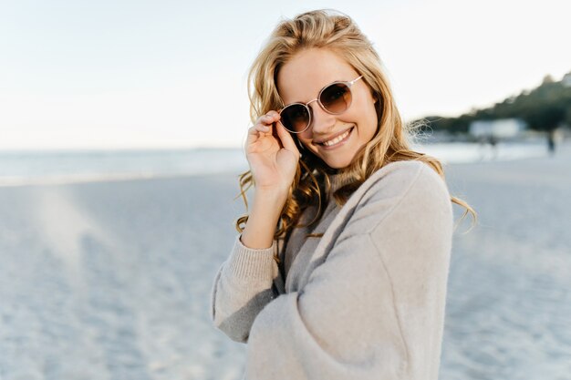 woman in pink sweater puts in brown sunglasses