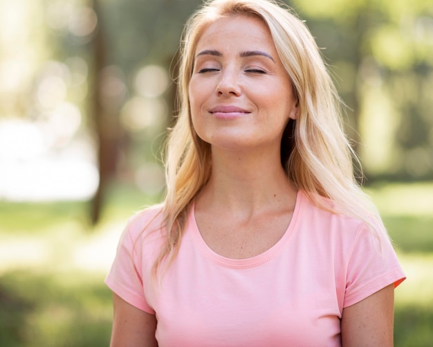 Woman in pink t-shirt holding her eyes closed