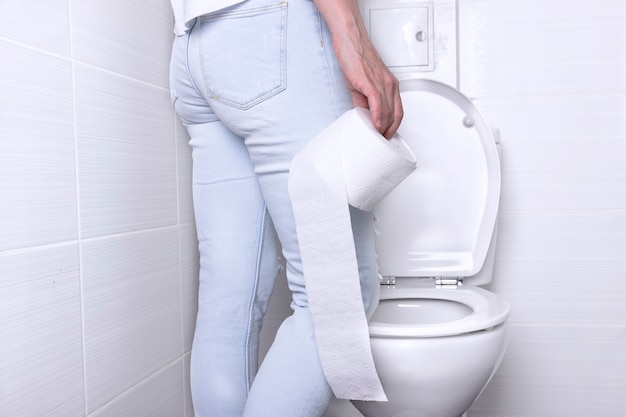 A woman wearing white jeans is pissing in the public toilet