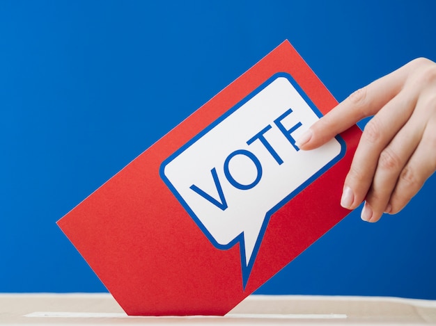 Женщина кладет свой избирательный бюллетень в ящик для выборов