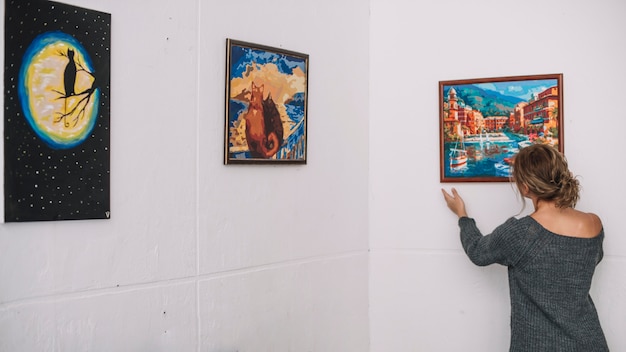 Woman placing picture on wall