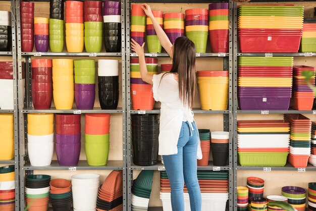 Woman placing stacked flowering pots in shelf