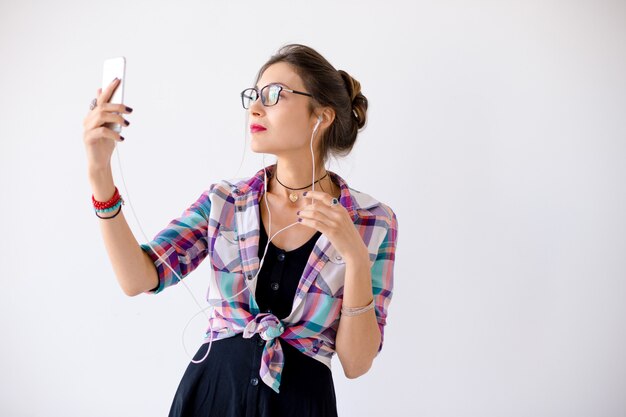 Woman in a plaid shirt in glasses plaing with headphones