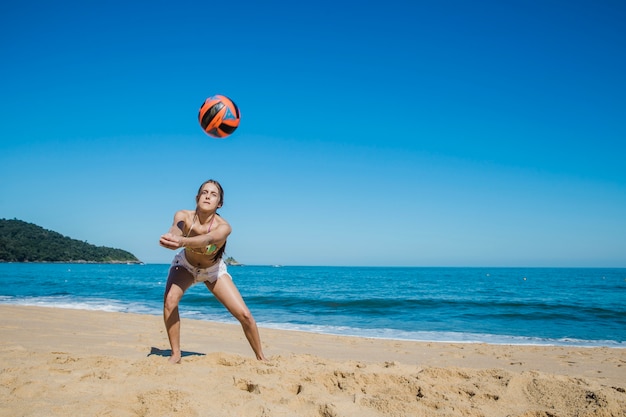 Женщина играет пляжный волейбол на пляже