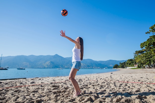 Женщина играет в пляжный волейбол