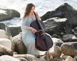 Free photo woman playing cello by the sea