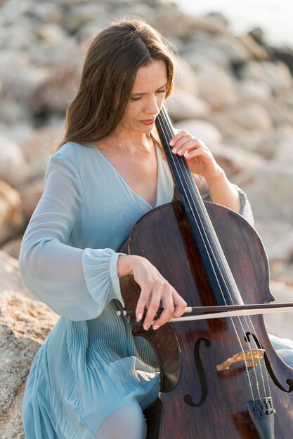 Woman playing cello on rocks
