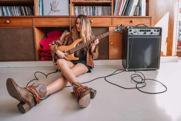 Woman playing electric guitar on floor