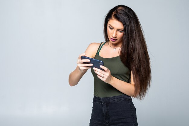 Женщина играет в игры в своем мобильном телефоне изолированы