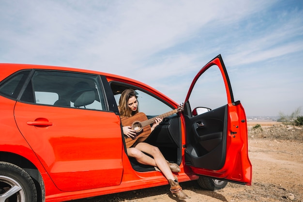 Woman playing guitar in car