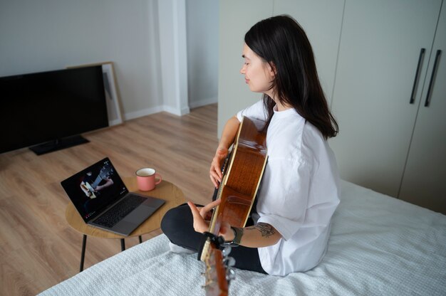 検疫中に自宅でギターを弾く女性